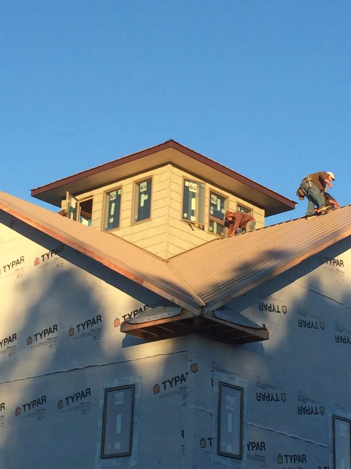 Roofers working around a rooftop cupola on a new metal roof at sunset — Roof Waterproofing in Andrews by Roofing Brothers